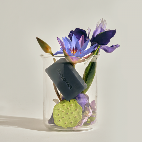 DONGGUBAT Field Blooming Perfume Shampoo Bar Repair 80g displayed with purple flowers in a glass vase.