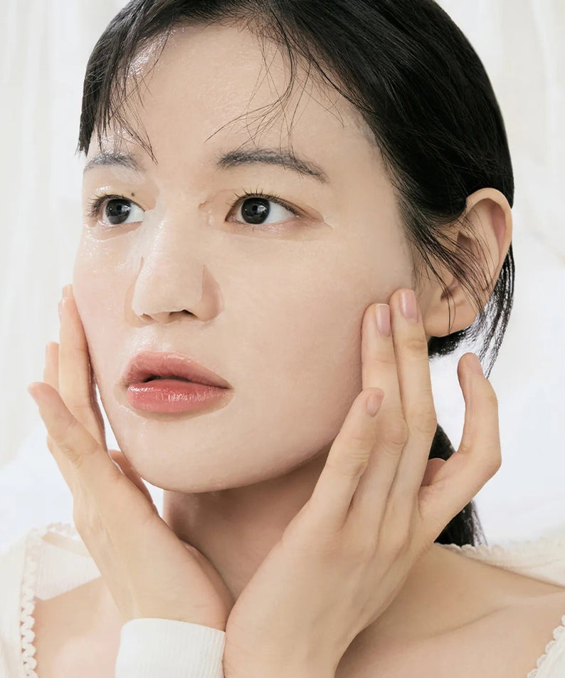 Woman using DR.ALTHEA Cushion Veil Calming Mask (4ea) for soothing skin care.