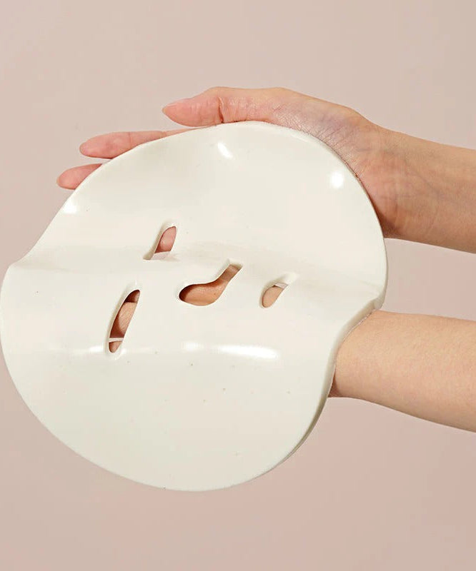 Person holding DR.CEURACLE Expert Collagen Firming Modeling Mask 30g, showcasing the smooth texture of the skincare product.