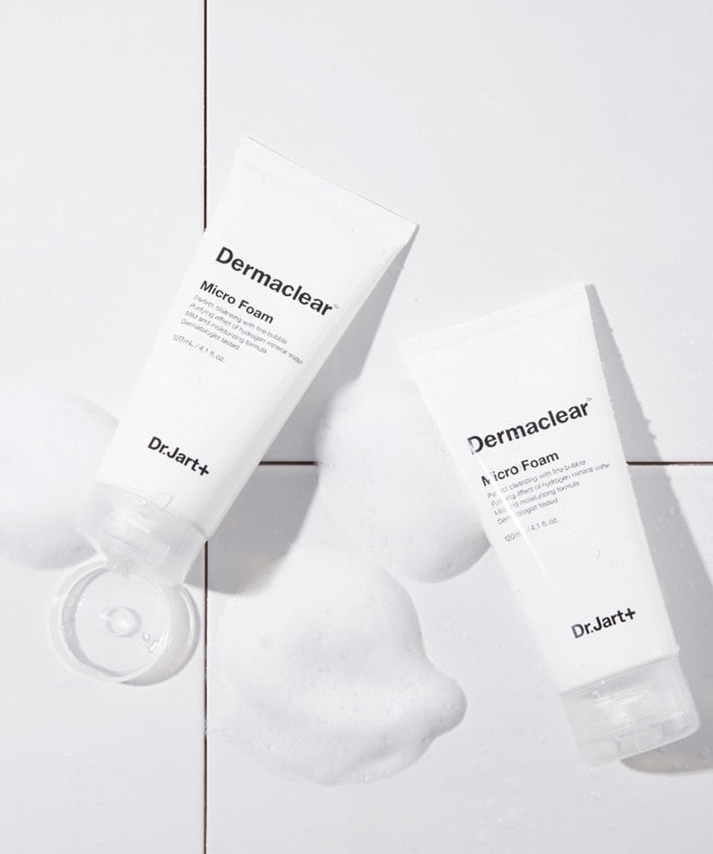 Two tubes of DR.JART+ DermaClear Micro Foam 120ml on a tiled surface with foamy bubbles.