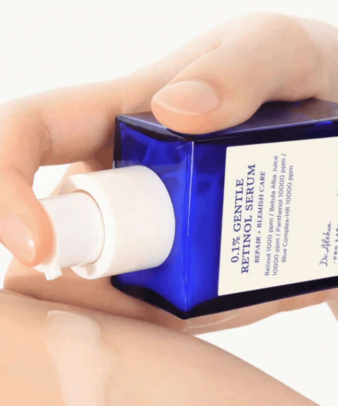 Hands holding and applying DR.ALTHEA 0.1% Gentle Retinol Serum 30ml from a blue bottle.