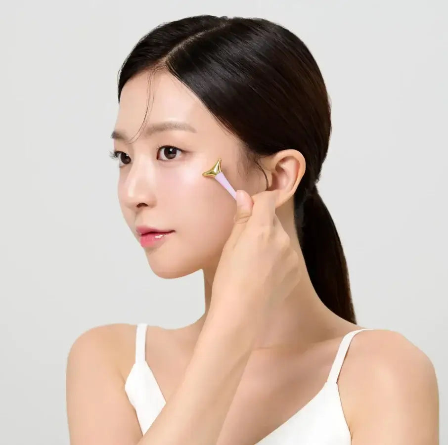 Woman applying DR.CEURACLE Vegan Active Berry Firming Eye Cream to cheek with roller