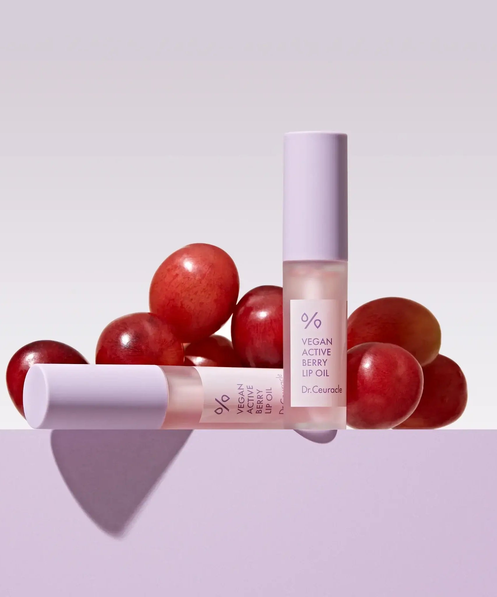 DR.CEURACLE Vegan Active Berry Lip Oil with grape background, nourishing lip care product displayed elegantly.