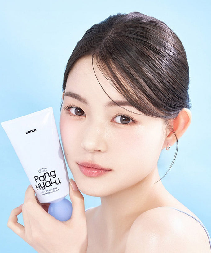 Woman holding EDIT.B Moisture Barrier Pang Hyaluronic Acid Pathenol Cream 100ml against blue background.