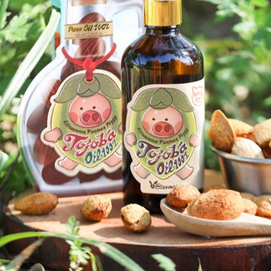 ELIZAVECCA Farmer Piggy Jojoba Oil 100% 100ml bottle with nuts displayed outdoors