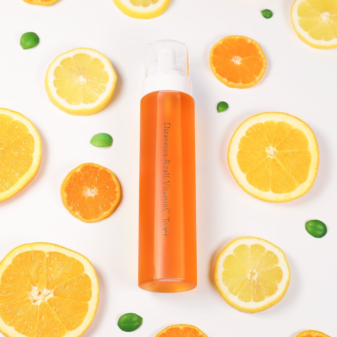 ELIZAVECCA Real One Vitamin C Toner 200ml bottle surrounded by citrus fruits on white background