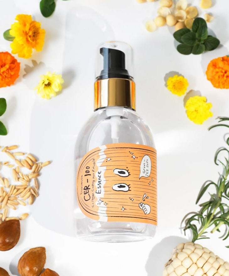 ELIZAVECCA Cer-100 Collagen Coating Hair A+ Massage Essence 150ml bottle surrounded by natural ingredients and flowers.