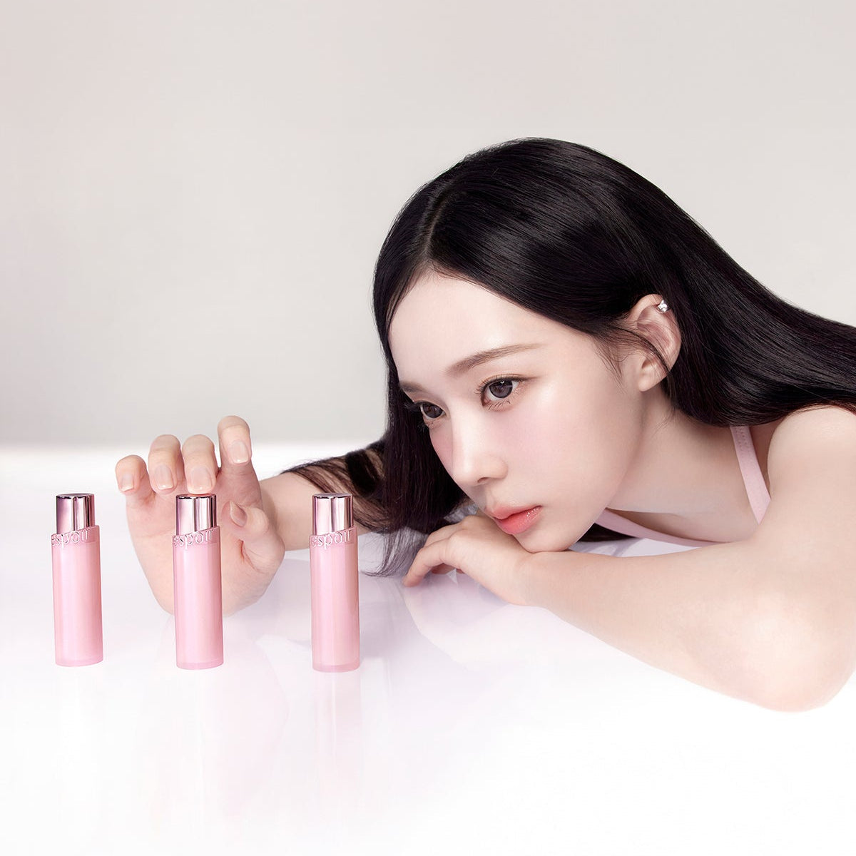 Model with ESPOIR Bare Glow Lip Balm showcasing pink packaging.