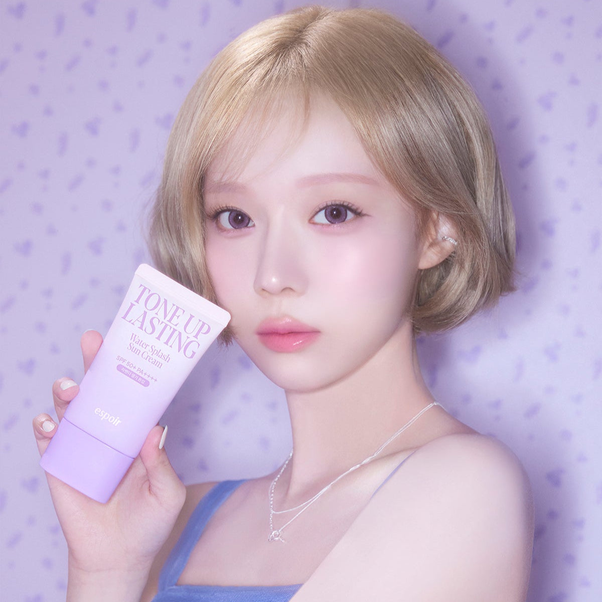 ESPOIR Water Splash Sun Cream Tone Up Lasting SPF 50+ PA++++ held by a model with purple background