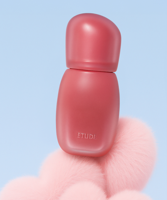 ETUDE Cozy Fixing Tint 4g in pink bottle, standing on fluffy pink surface against blue background.