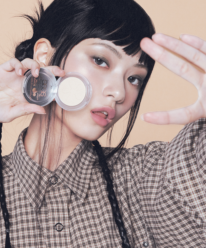 Model showcasing ETUDE Face Brightener product with edgy makeup look against neutral background.