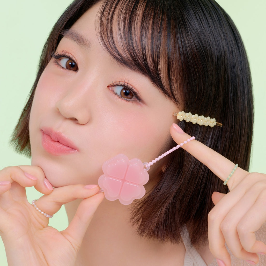 Model holding ETUDE Lucky Lip Ham Cheek [Positive Love Edition] in front of face, showing pink product and youthful, fresh style