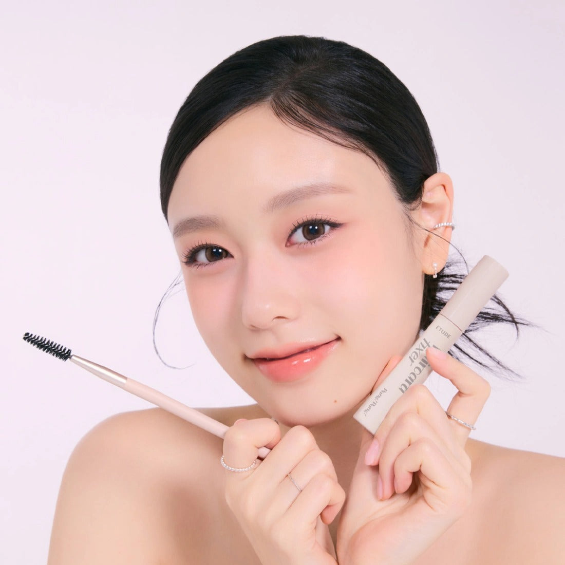 Woman holding ETUDE Pangpang Hair Cara Fixer 10ml with applicator, highlighting natural brow enhancement.