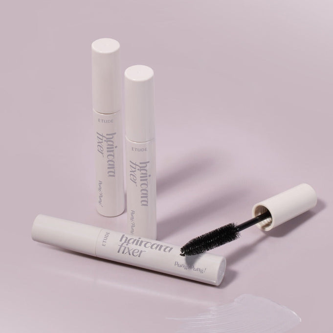 ETUDE Pangpang Hair Cara Fixer 10ml tube with wand against a soft pink background.