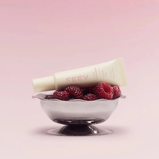 FEEV Fluffy Cheek Blush 10g tube displayed on raspberries in a bowl with a soft pink background.