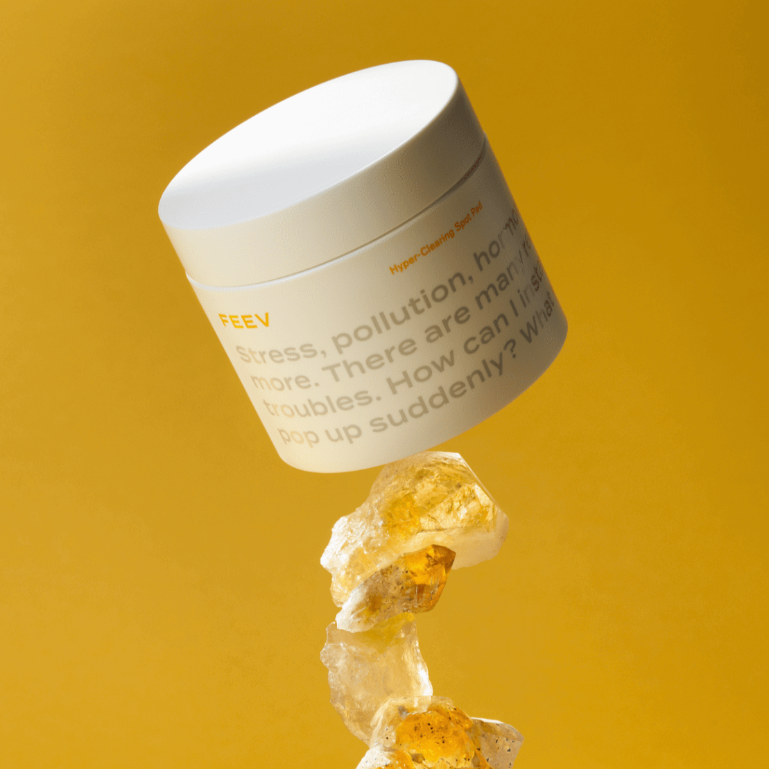 FEEV Hyper-Clearing Spot Pads 100ml on display with a background of golden stones and a vibrant yellow backdrop.