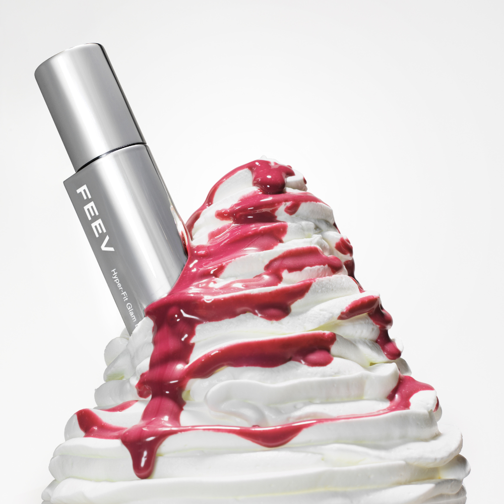 FEEV Hyper-Fit Glam Drop beauty product with rich texture and glamorous design, enhanced by vibrant syrup and whipped cream backdrop.