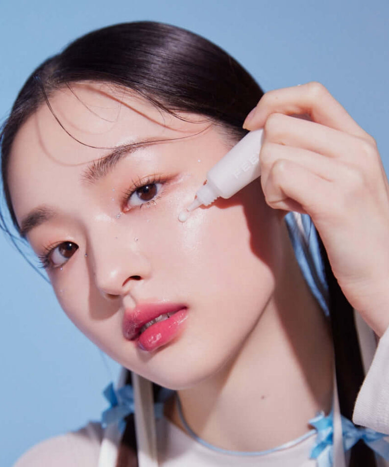 Woman applying FEEV Hyper-Fit Shimmering Serum on her cheek for radiant skin enhancement