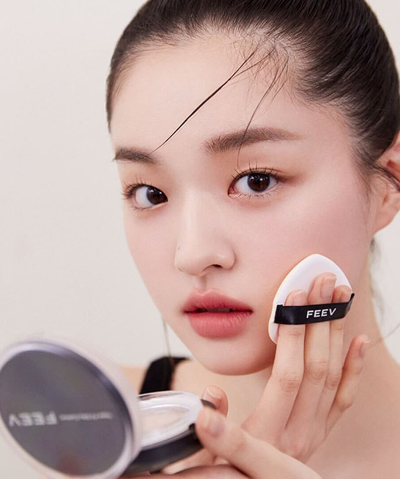 Woman applying FEEV Hyper-Fit Silky Cushion with makeup sponge for flawless coverage.