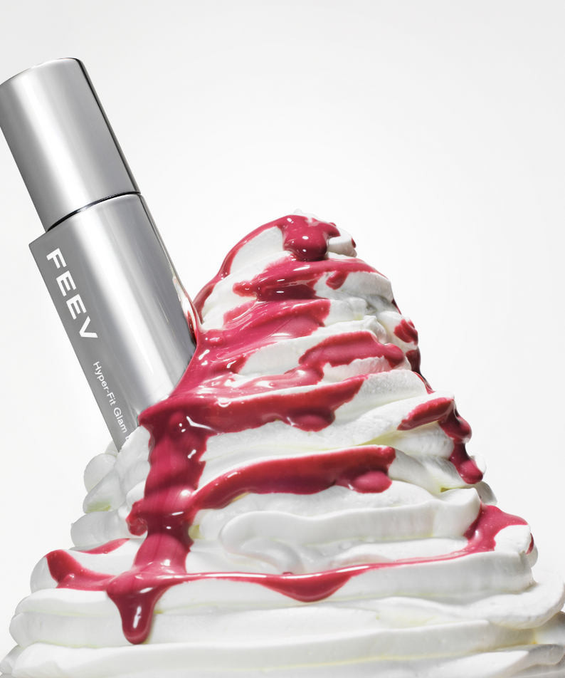 FEEV Hyper-Fit Glam Drop beauty product with rich texture and glamorous design, enhanced by vibrant syrup and whipped cream backdrop.