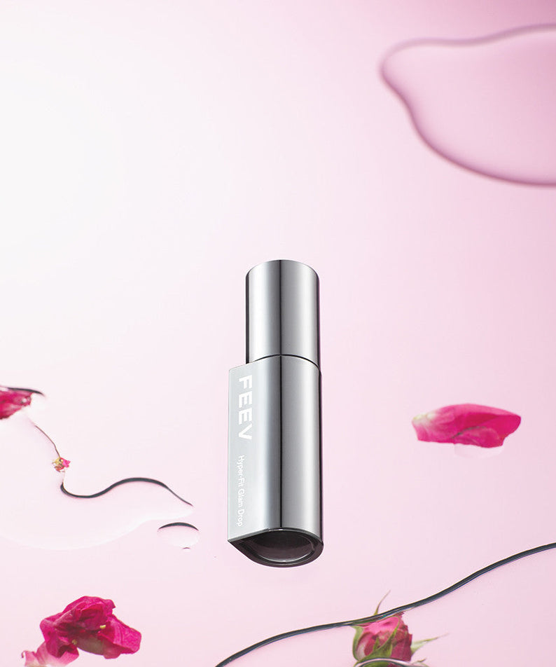 FEEV Hyper-Fit Glam Drop bottle with pink background and rose petals, highlighting luxury skincare product.