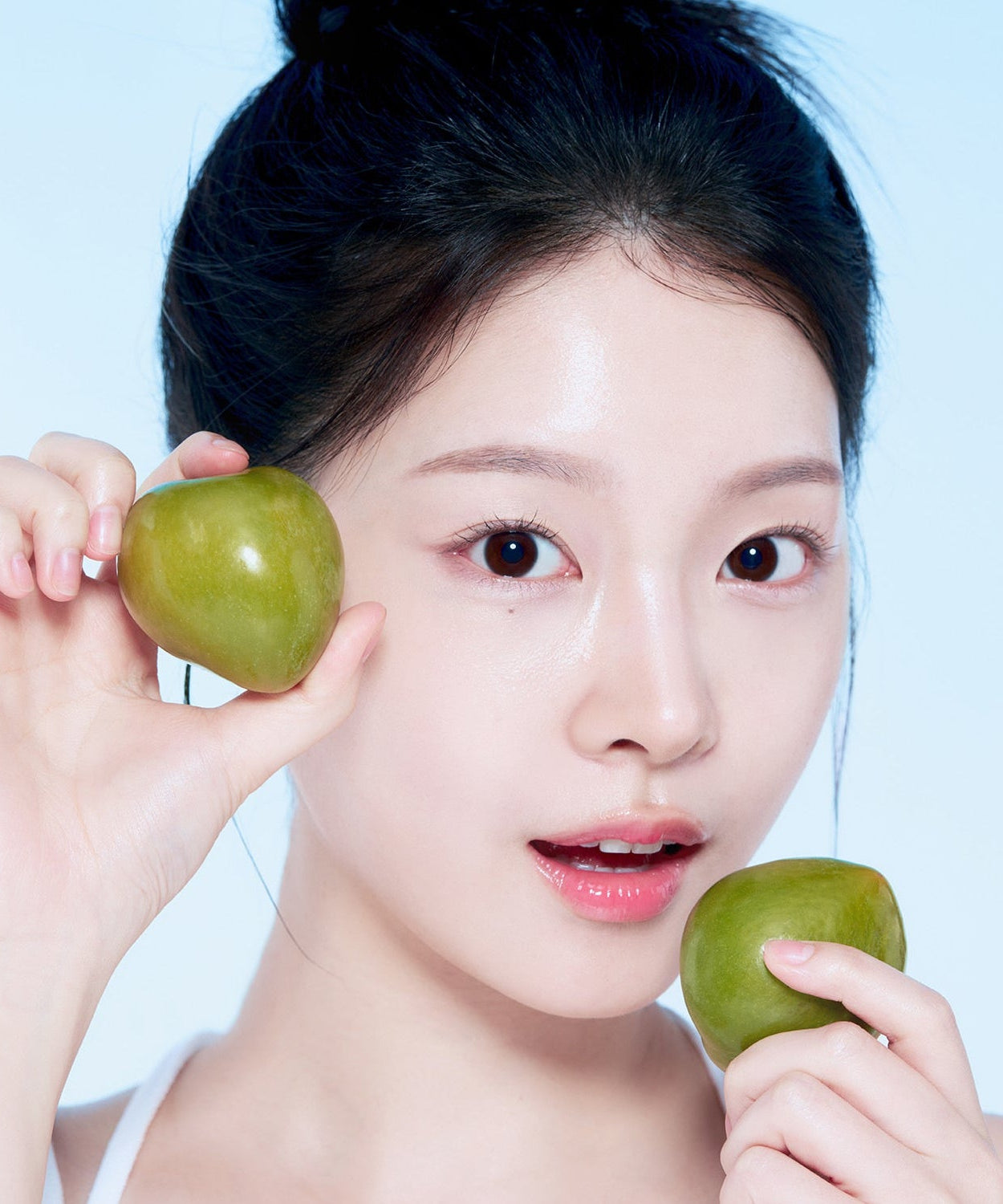Woman holding green plums, promoting skincare with natural ingredients