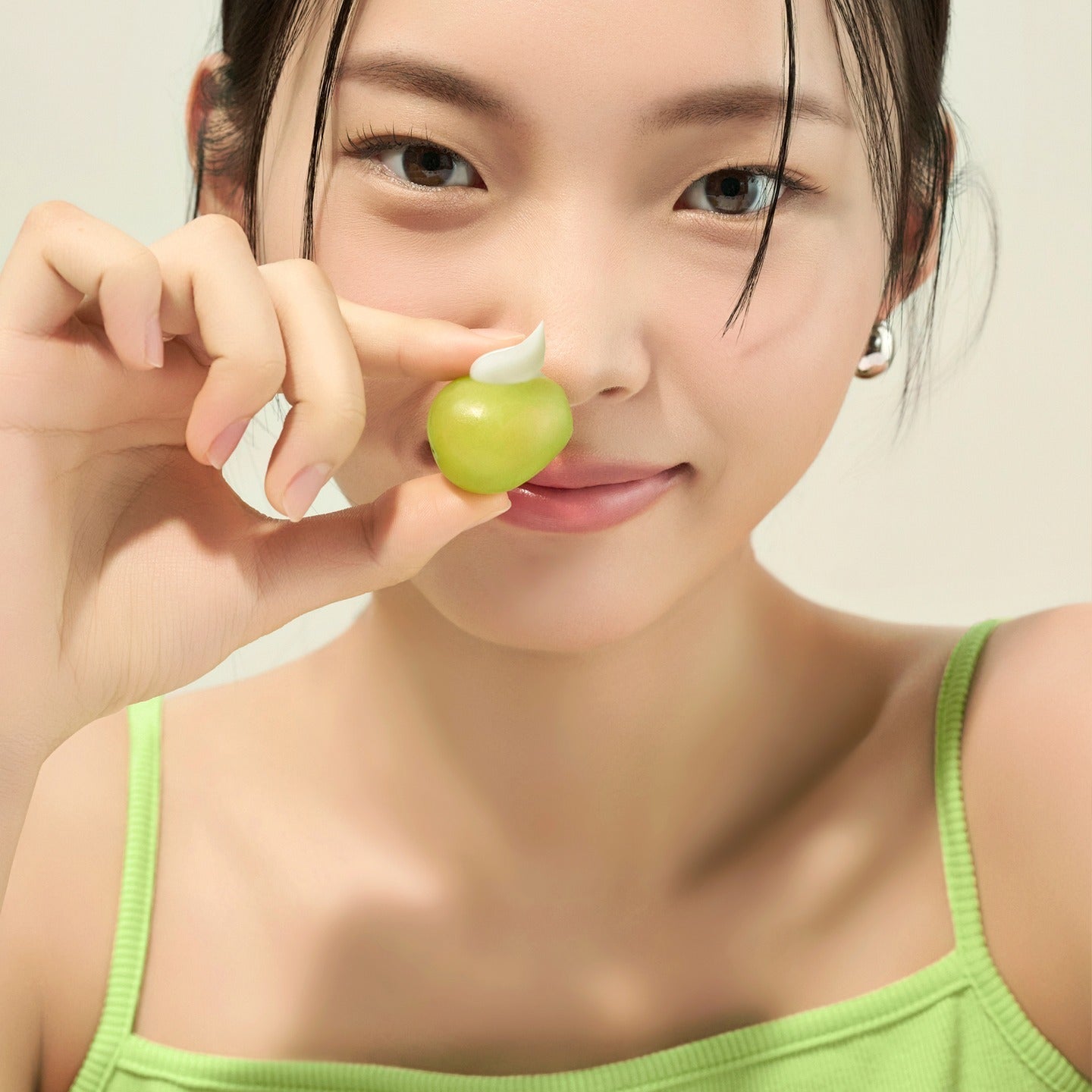 Woman holding skincare representing FRUDIA Avocado Greenery Relief Sun Cream 50g