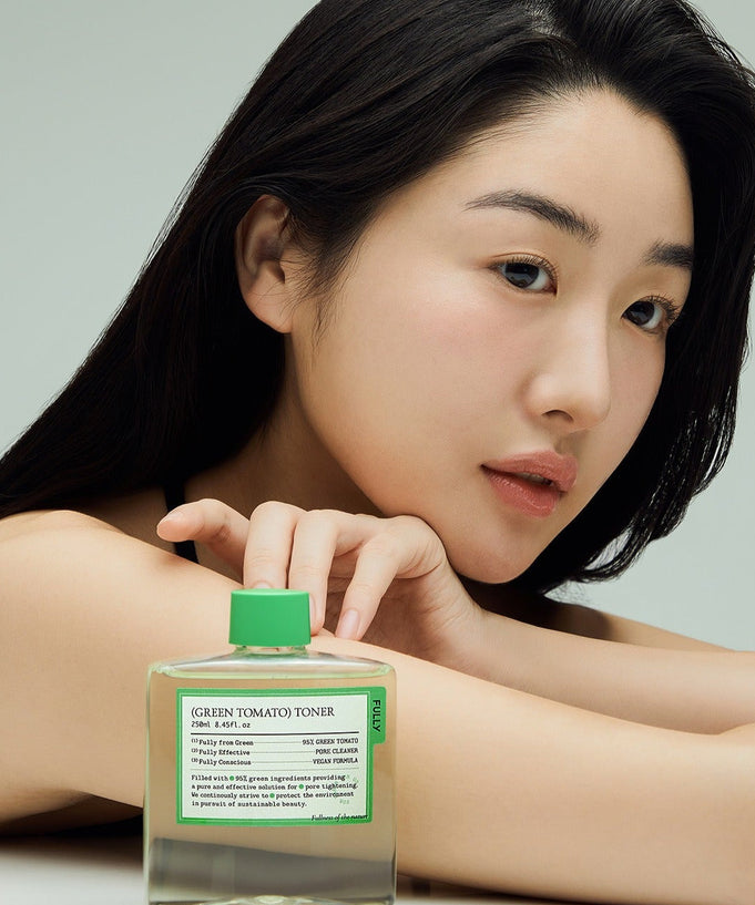 Woman holding a bottle of FULLY Green Tomato Toner 250ml, showcasing its packaging and design.