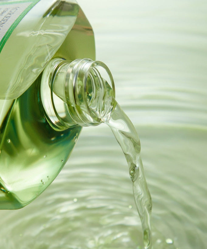 FULLY Green Tomato Toner 250ml being poured from the bottle into clear water, enhancing skincare routine with natural ingredients.