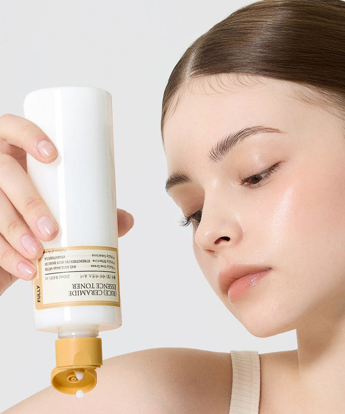 Woman using FULLY Rice Serum Essence Toner 250ml, holding the bottle to apply product to her skin