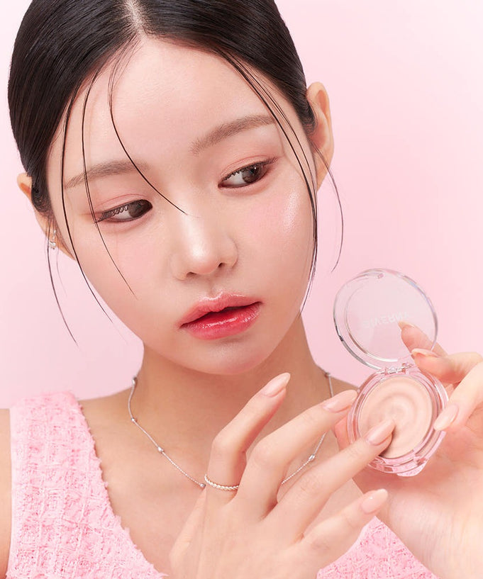 Woman applying GIVERNY Dewy Voluming Highlighter 3g to cheek, showcasing makeup product's voluminous effect on skin.