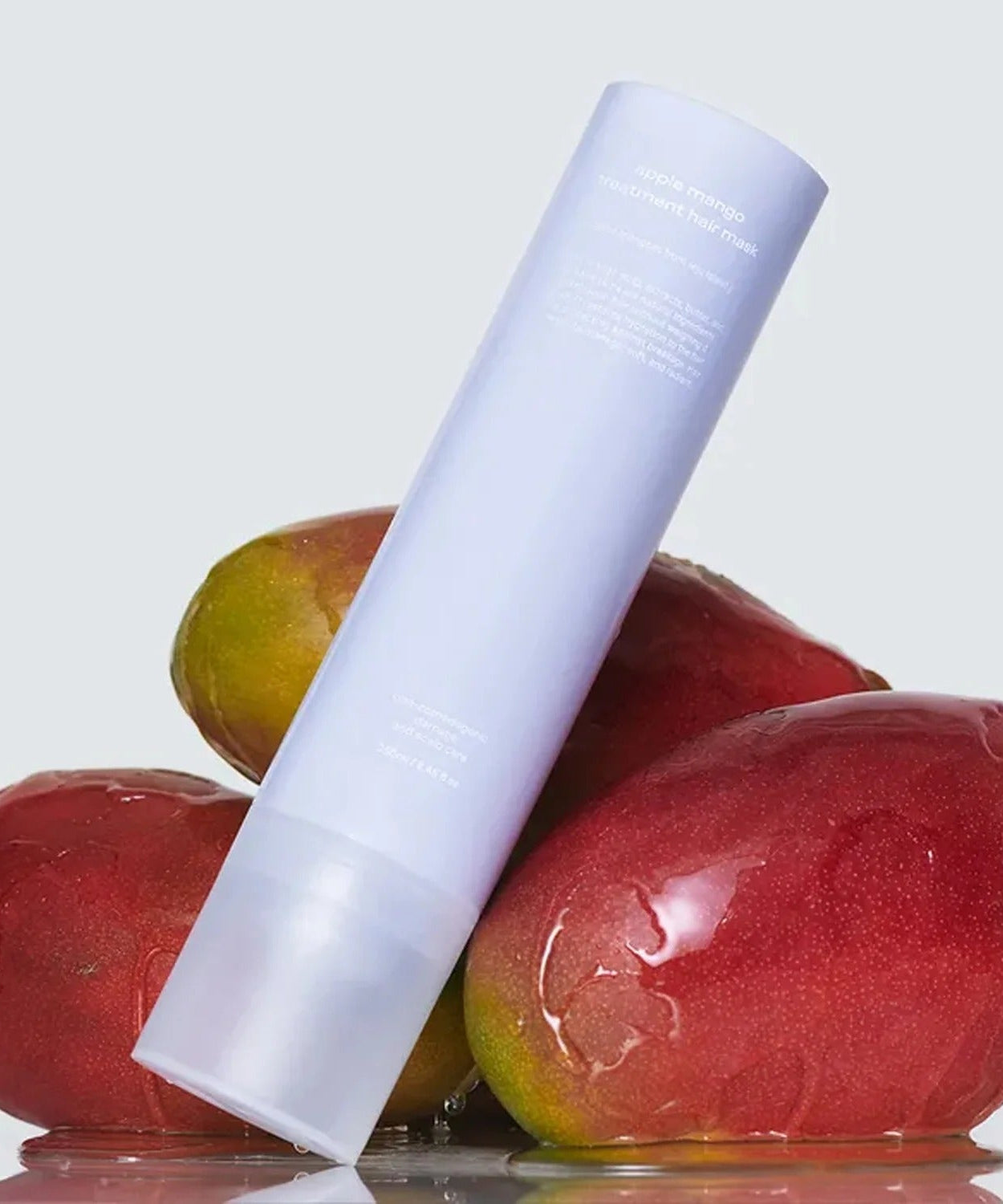 GLOW Apple Mango Hair Treatment 250ml bottle with fresh mangos in the background