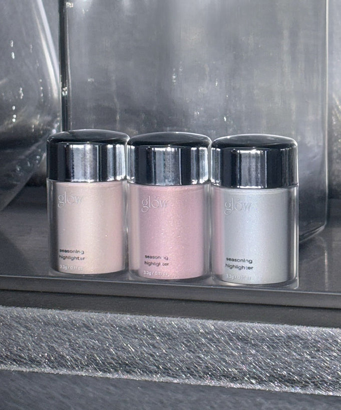 Three GLOW Seasoning Highlighter bottles in pink, silver, and beige shades on display.