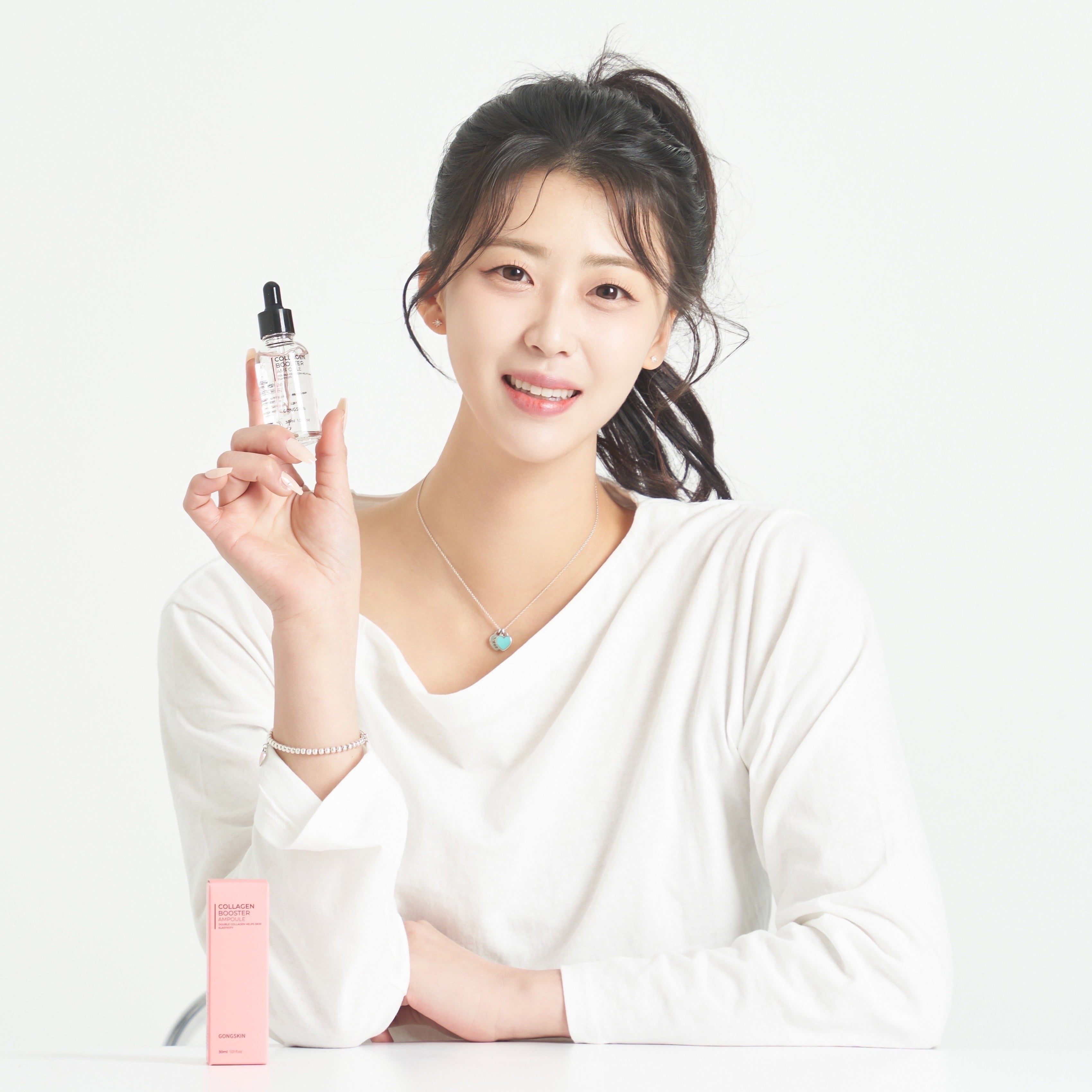 Woman holding GONGSKIN UV Tone-up Sunscreen 50ml with pink packaging on table