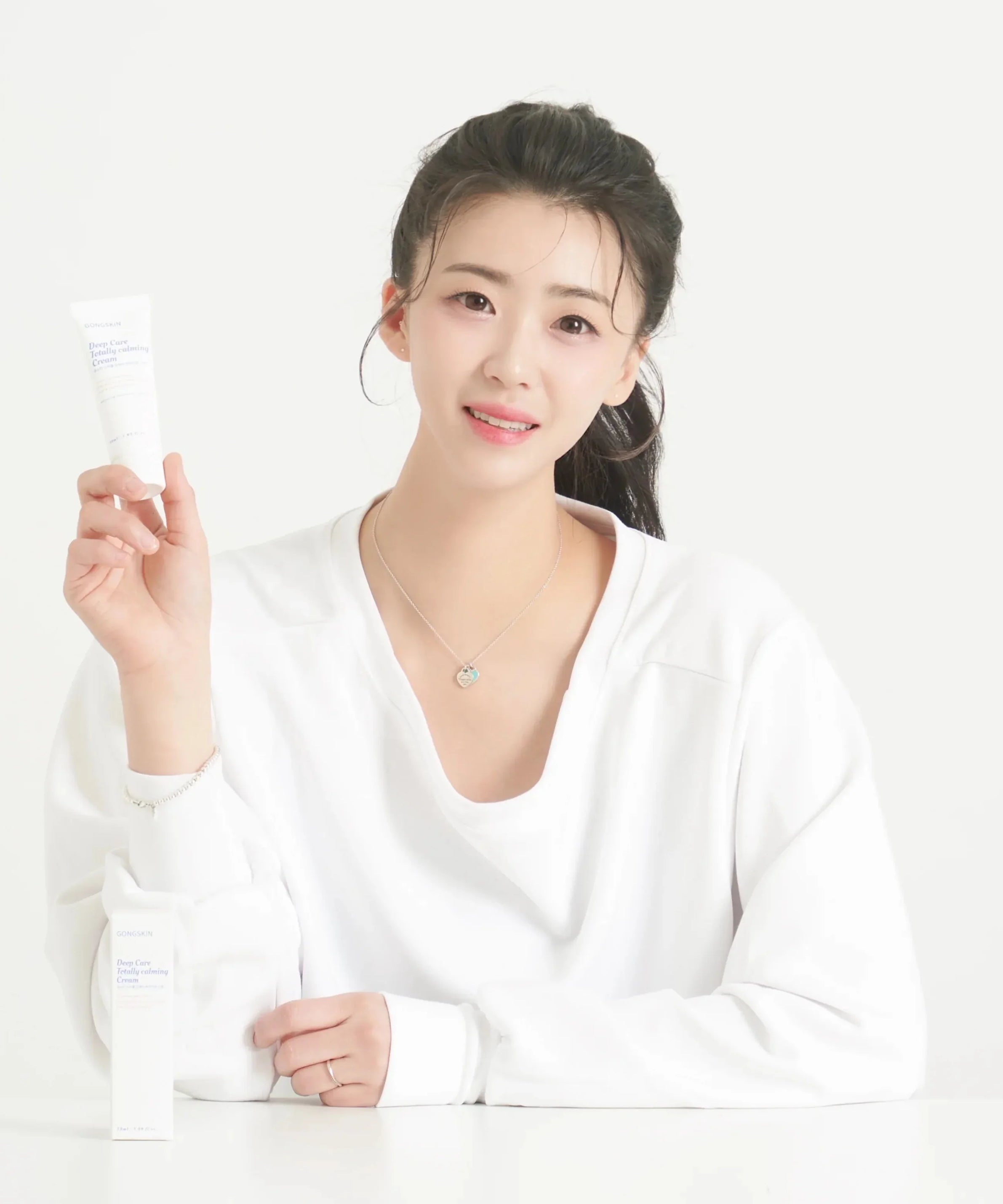 Woman holding GONGKIN Deep Care Totally calming Cream 50ml, skincare product.