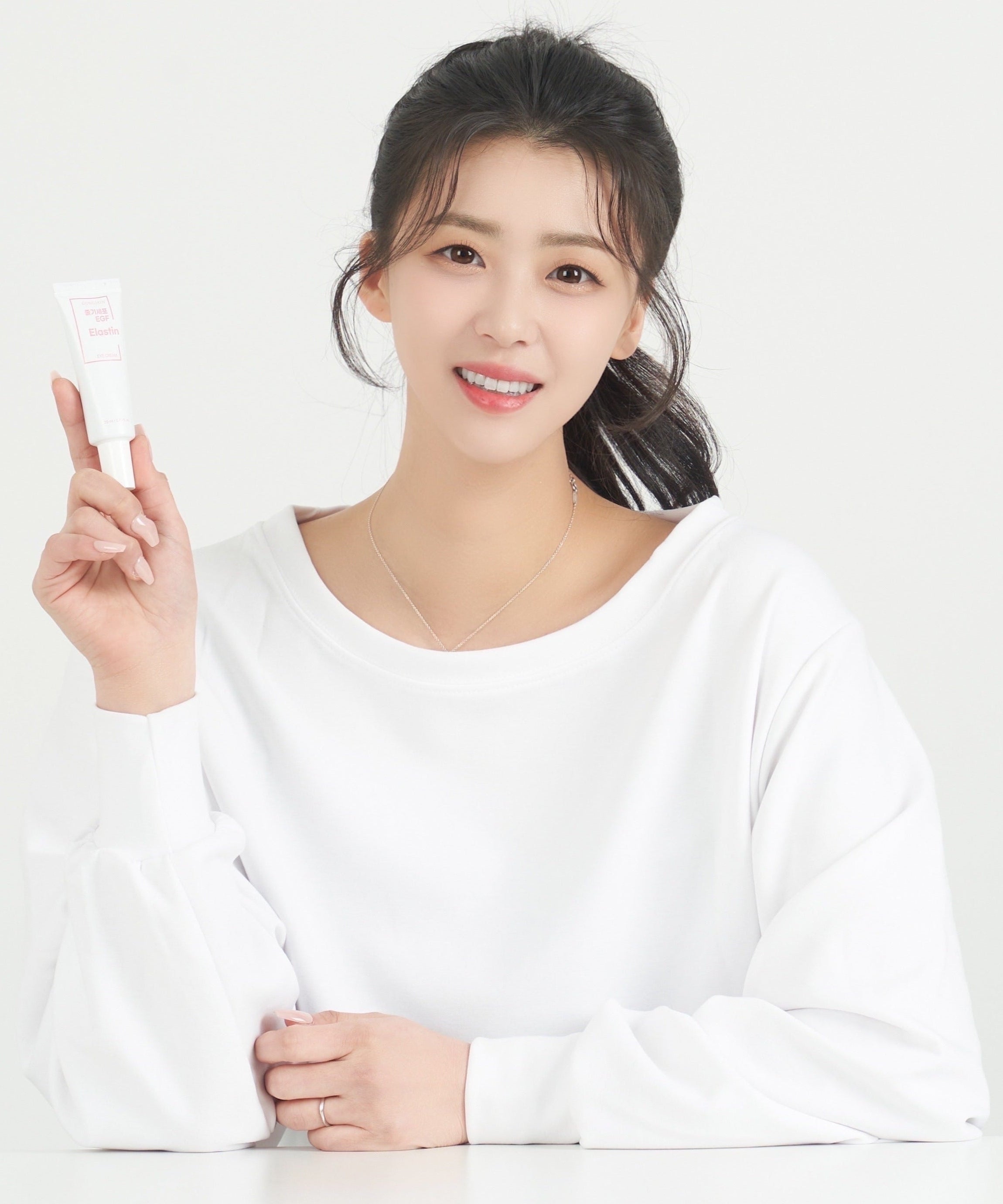 Person holding GONGSKIN Stem Cell EGF Elastin Eye Cream 20ml tube, smiling and wearing white shirt.