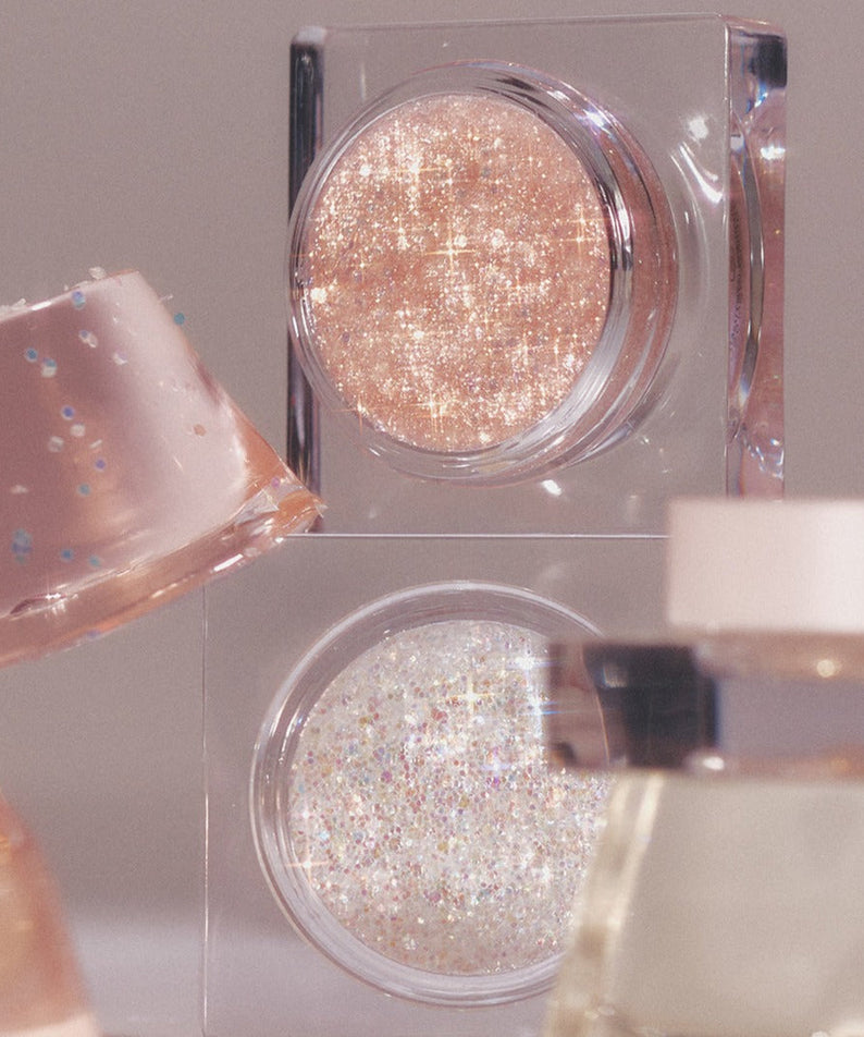 Close-up of GLINT Glitter Gel in shimmering pink and white shades, perfect for adding sparkle to your makeup collection.