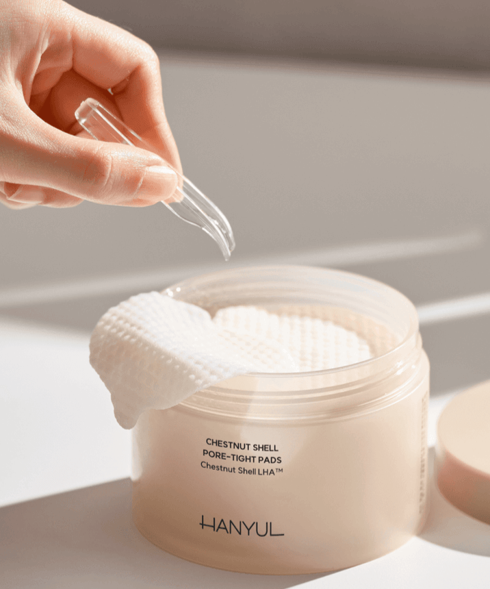 Hand using tweezers to pick up a pad from HANYUL Buddleberry Pore Tightening Pad jar on a white background.