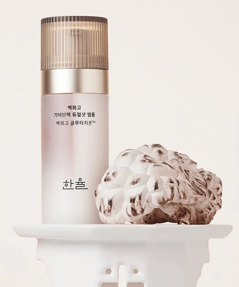 HANYUL Baekhwago Gimitanryuk Dual Shot Ampoule 45ml bottle on display with decorative plant.