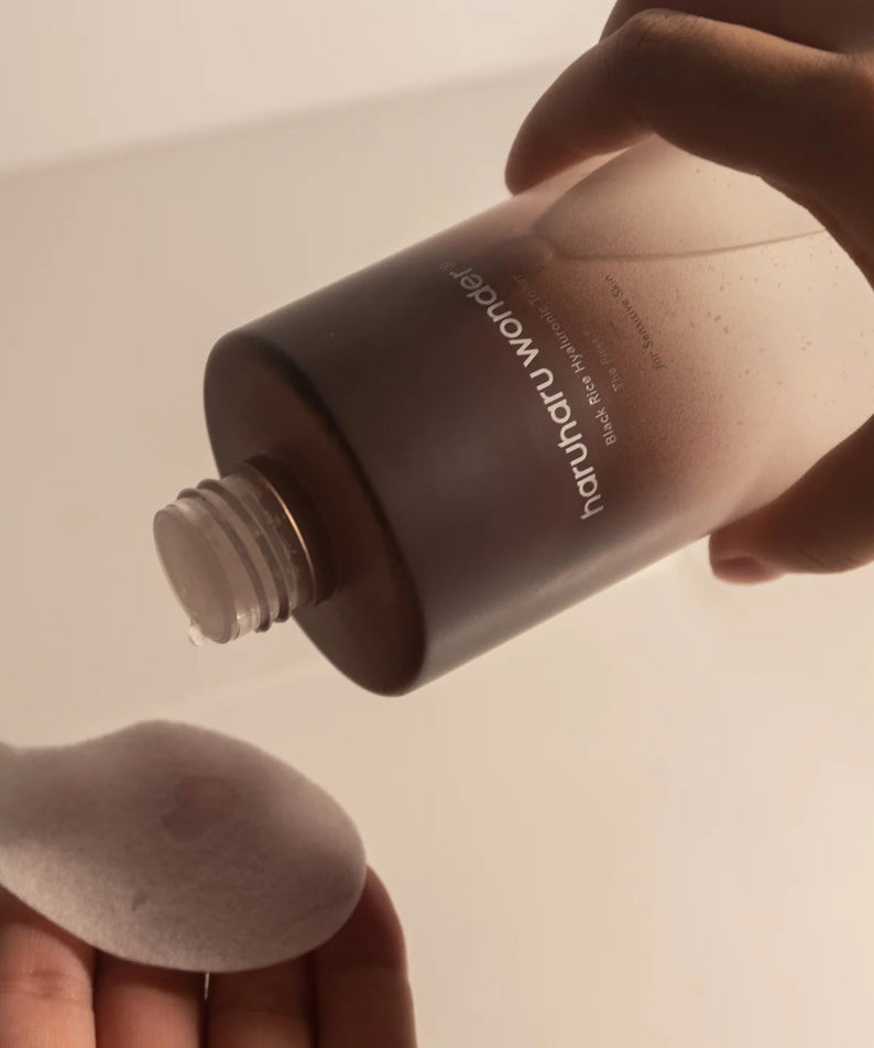 Pouring HARU HARU Black Rice Hyaluronic Toner Unscented 150ml onto a cotton pad.