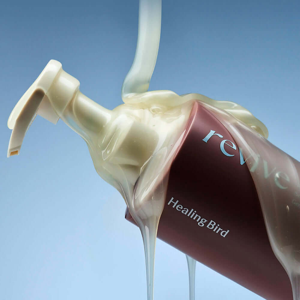 HEALING BIRD Revive Protein Shampoo + Deep Hair Mask bottle with creamy texture pouring out against blue background