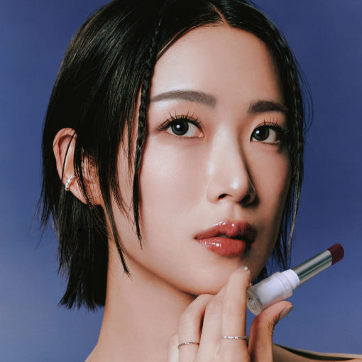 Person applying HEALUS Bare Lip Glow 4g with a thoughtful expression