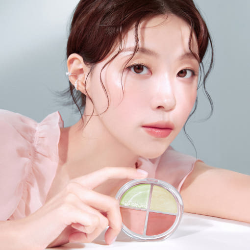 Woman holding HEALUS Breath Light Corrector 7g, showcasing four-color makeup palette in pink and green shades.