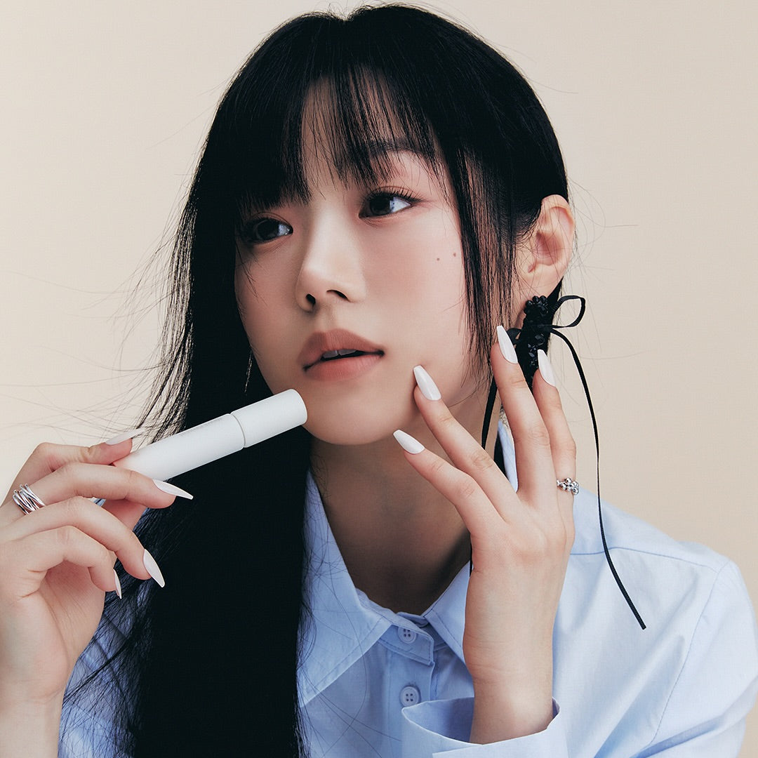 Person holding HEART PERCENT Dot On Mood All Cover Lip Base, emphasizing the product's sleek design and application style.