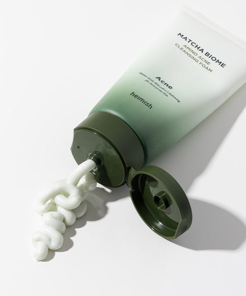 HEIMISH Matcha Biome Amino Acne Cleansing Foam 150g tube with foam oozing out on a white surface, skincare product image.