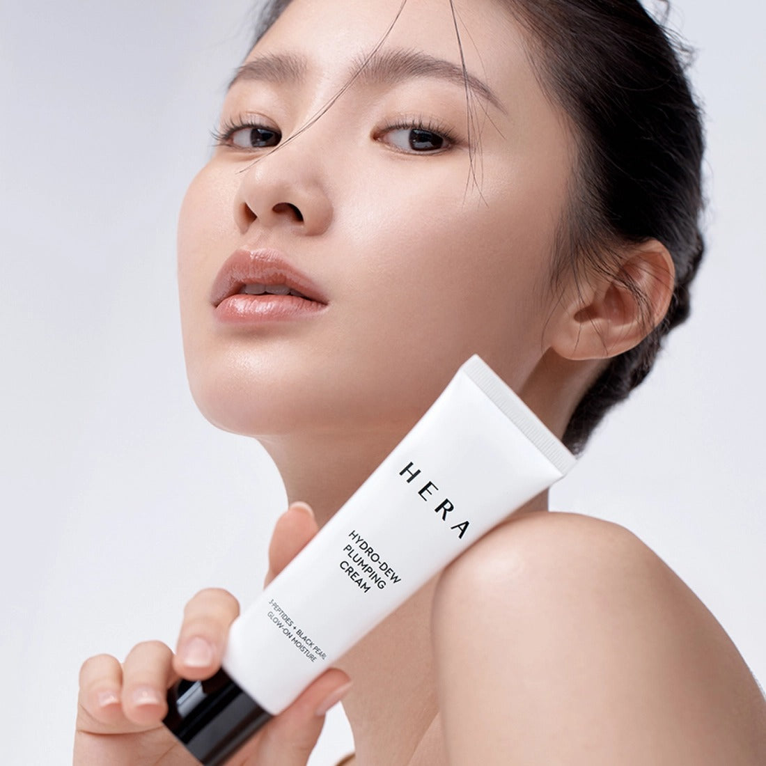 Woman holding HERA Hydro-Dew Plumping Cream 50ml with fresh, glowing skin