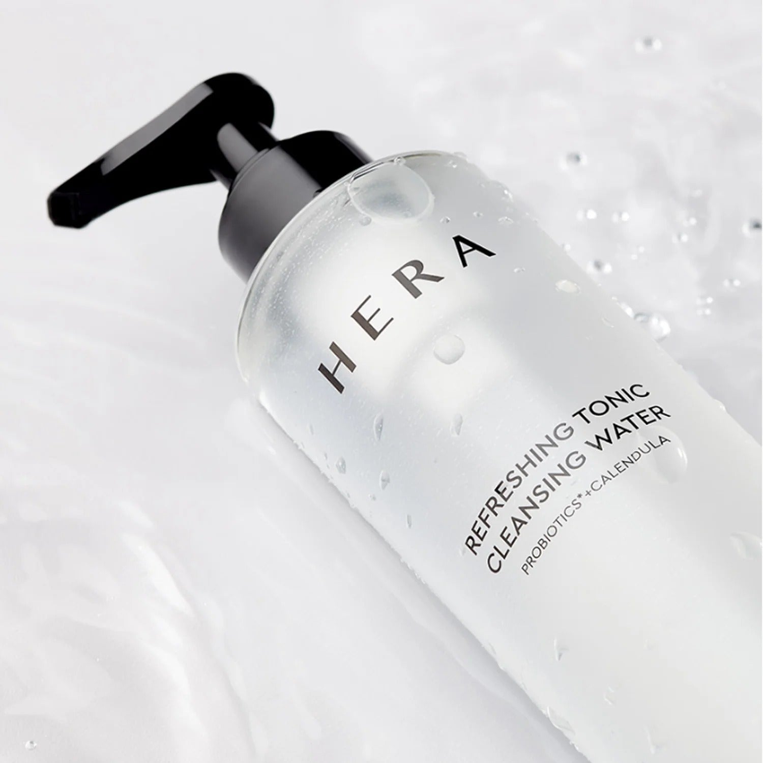HERA Refreshing Tonic Cleansing Water 200ml bottle on a white surface with water droplets.