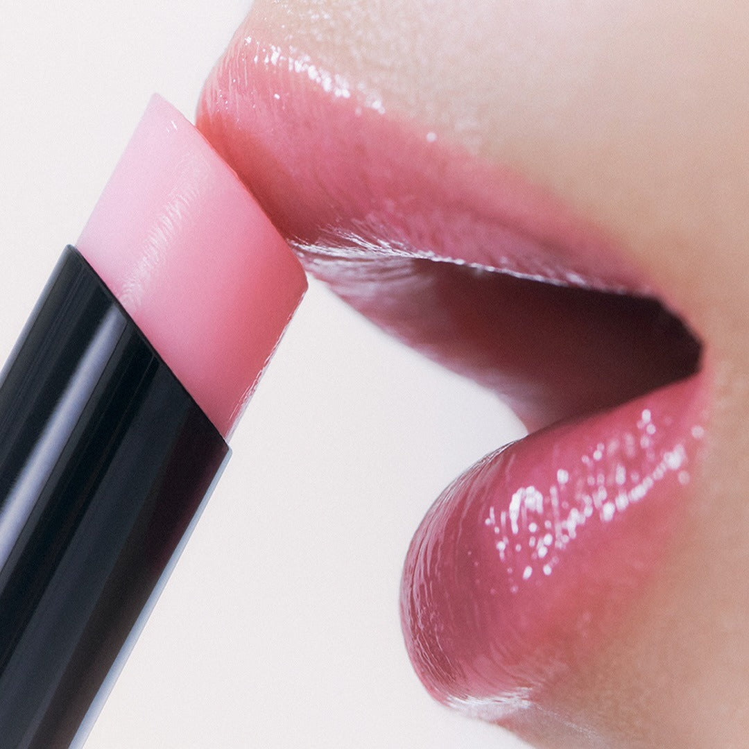 Close-up of lips applying HERA Sensual Nude Balm 3.5g for a natural look.