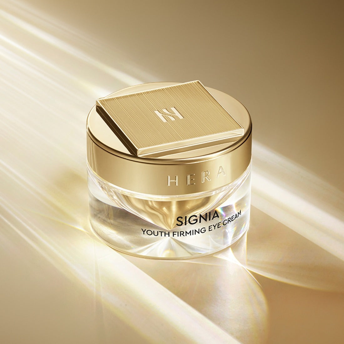 HERA Signa Youth Firming Eye Cream 30ml in elegant gold packaging on a light-reflective surface.