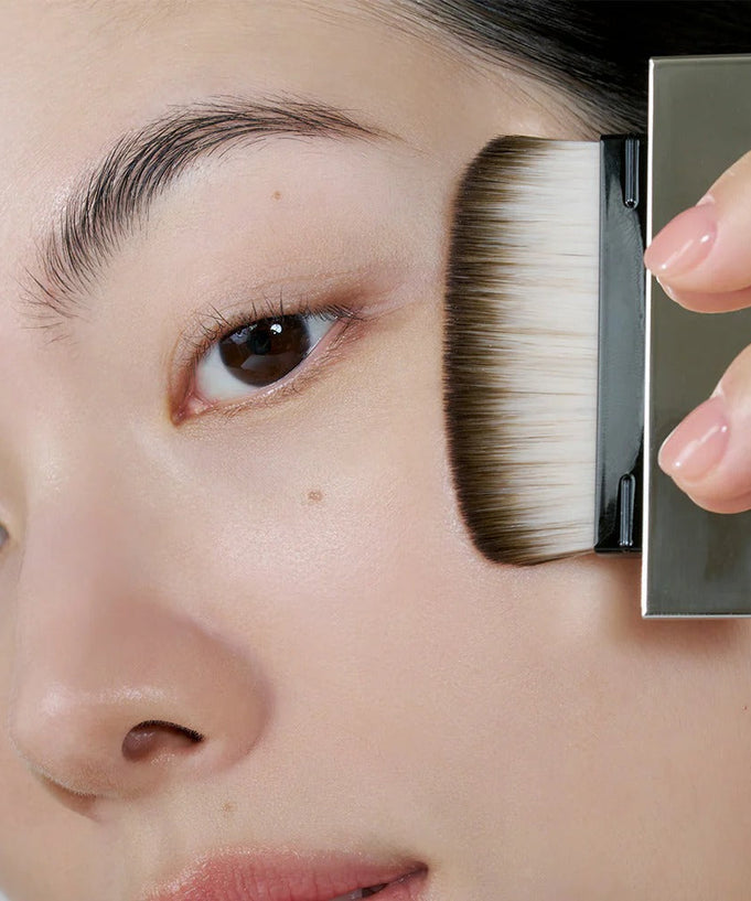 Applying makeup with HERA Airy Powder Primer 8.5g brush on cheek for smooth skin finish.